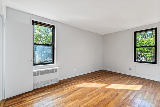 140-15 Holly Ave Unit 4E, Flushing, NY 11355 - empty room featuring radiator, light wood-style floors, healthy amount of natural light, and baseboards