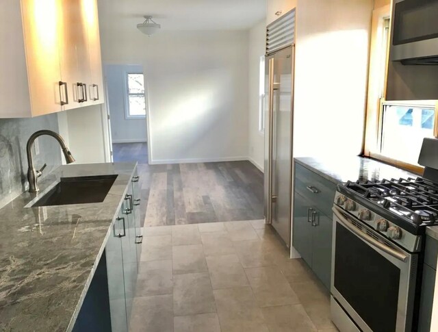 75-09 60th Pl, Glendale, NY 11385 - kitchen with appliances with stainless steel finishes, a sink, light stone countertops, tasteful backsplash, and baseboards