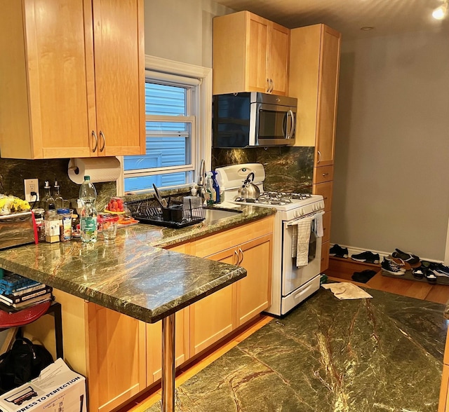 75-09 60th Pl, Glendale, NY 11385 - kitchen with white range with gas stovetop, stainless steel microwave, tasteful backsplash, dark stone counters, and a peninsula