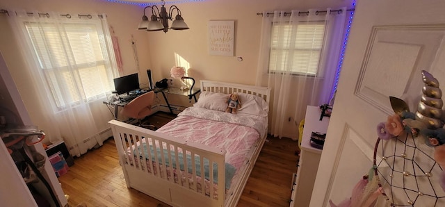 238 Adams St, Deer Park, NY 11729 - bedroom with wood finished floors, a chandelier, multiple windows, and baseboard heating