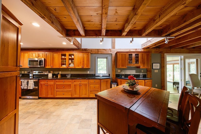 1900 Home, Sheffield, MA 01230 - kitchen with stainless steel appliances, brown cabinetry, wood ceiling with exposed beams, glass insert cabinets, and dark countertops