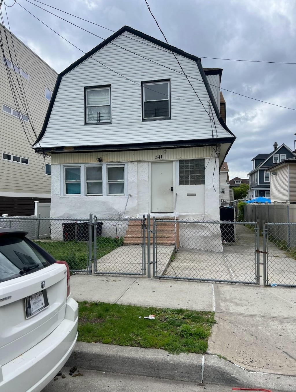 341 Bch 67th St, Far Rockaway, NY 11692 - colonial inspired home with a gambrel roof, a gate, and a fenced front yard