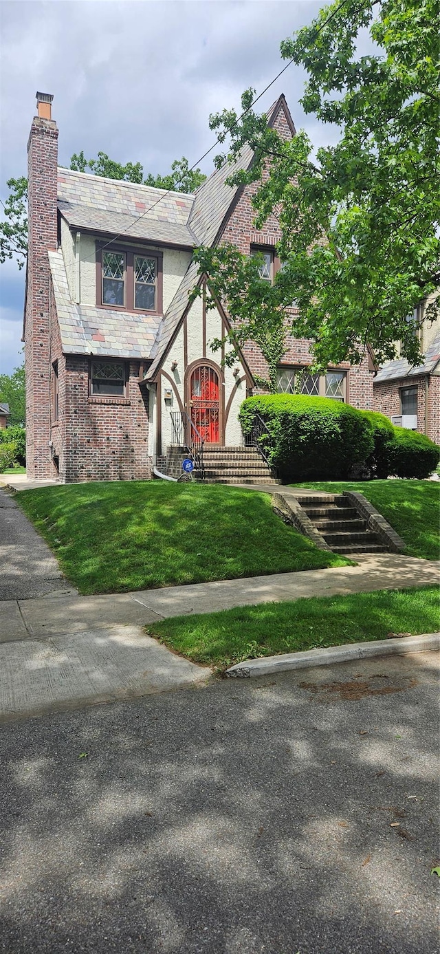 16023 28th Ave, Flushing, NY 11358 - tudor home featuring a chimney, brick siding, a high end roof, and a front lawn
