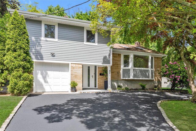 27 Meadowfield Ln, Glen Cove, NY 11542 - view of front of home with asphalt driveway, brick siding, an attached garage, and a chimney