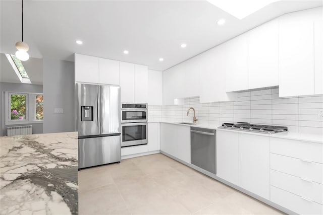 27 Meadowfield Ln, Glen Cove, NY 11542 - kitchen with stainless steel appliances, a skylight, radiator, a sink, and white cabinetry