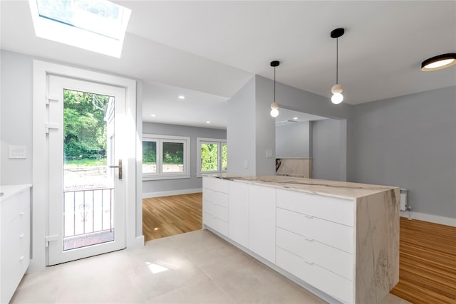 27 Meadowfield Ln, Glen Cove, NY 11542 - kitchen with modern cabinets, white cabinets, pendant lighting, light stone countertops, and a skylight