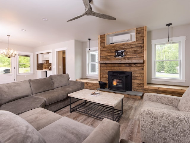 123 Wildwood Way, Forestburgh, NY 12777 - living area featuring wood finished floors, a wall mounted air conditioner, a ceiling fan, a chandelier, and a wood stove