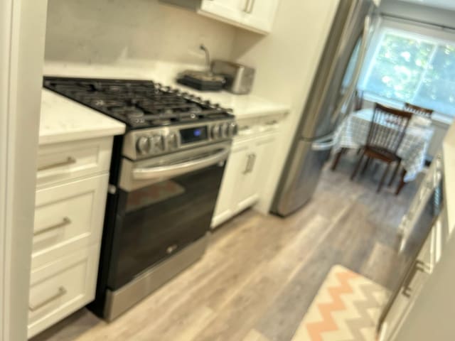 38 Tulip Ct, Nanuet, NY 10954 - kitchen featuring stainless steel range with gas stovetop, light countertops, white cabinetry, and light wood-type flooring