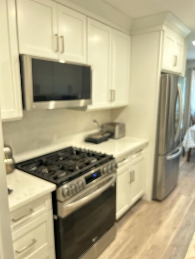 38 Tulip Ct, Nanuet, NY 10954 - kitchen featuring appliances with stainless steel finishes, white cabinetry, light countertops, and light wood-style floors