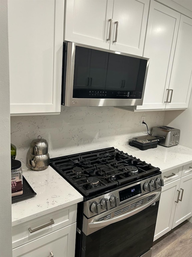 38 Tulip Ct, Nanuet, NY 10954 - kitchen featuring stainless steel appliances, white cabinetry, and light stone counters