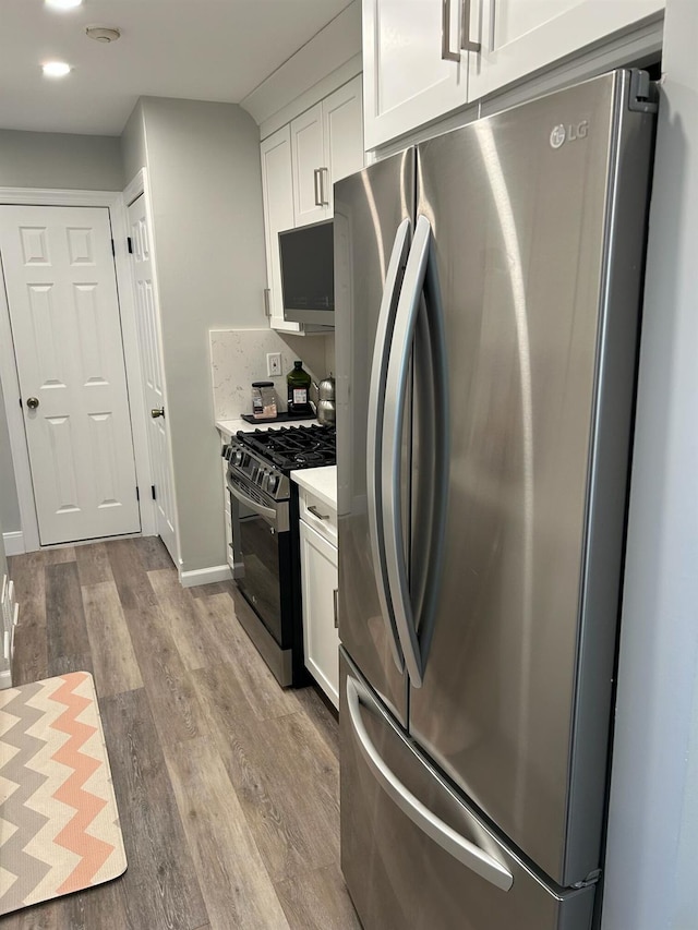 38 Tulip Ct, Nanuet, NY 10954 - kitchen with stainless steel appliances, wood finished floors, white cabinets, light countertops, and recessed lighting