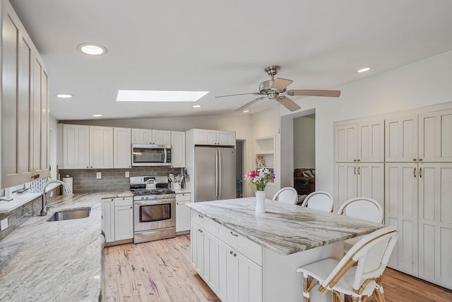 215 Lyman Rd, East Patchogue, NY 11772 - kitchen with stainless steel appliances, a sink, a breakfast bar area, a skylight, and decorative backsplash