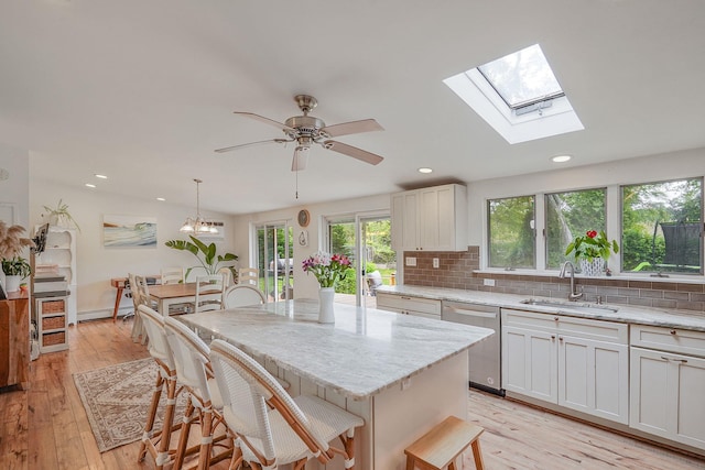 215 Lyman Rd, East Patchogue, NY 11772 - kitchen with a sink, stainless steel dishwasher, backsplash, light stone countertops, and light wood-style floors