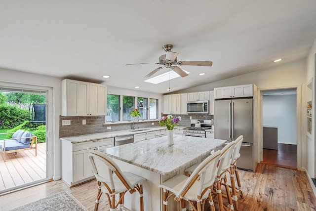 215 Lyman Rd, East Patchogue, NY 11772 - kitchen featuring stainless steel appliances, a sink, ceiling fan, tasteful backsplash, and a kitchen bar