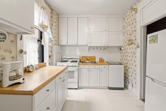 33-21 82nd St Unit 51, Jackson Heights, NY 11372 - kitchen featuring white appliances, wallpapered walls, white cabinets, a sink, and decorative backsplash