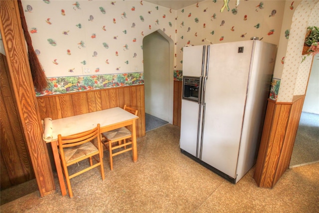 115-31 237th St, Elmont, NY 11003 - kitchen featuring white refrigerator with ice dispenser, wallpapered walls, a wainscoted wall, and arched walkways