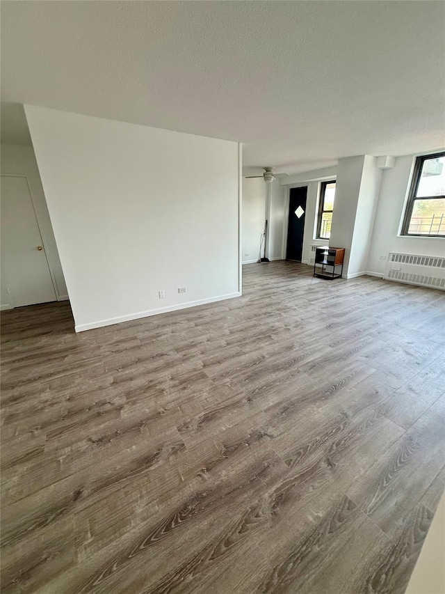 1966 Newbold Ave Unit 405, Bronx, NY 10472 - unfurnished living room featuring radiator heating unit, wood finished floors, and a textured ceiling