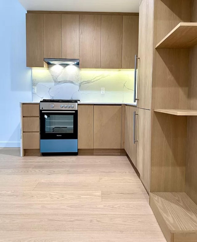 3005 Vernon Blvd Unit 4H, Astoria, NY 11102 - kitchen featuring stainless steel gas range oven, under cabinet range hood, light wood-style floors, light countertops, and modern cabinets