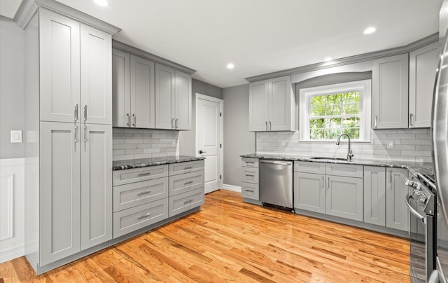 1850 Voshage St, Baldwin, NY 11510 - kitchen with appliances with stainless steel finishes, gray cabinetry, a sink, light wood finished floors, and dark stone countertops