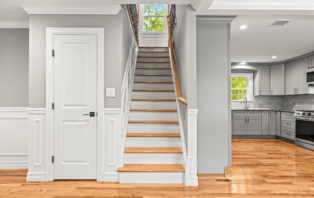 1850 Voshage St, Baldwin, NY 11510 - stairway with wood finished floors, ornamental molding, and recessed lighting