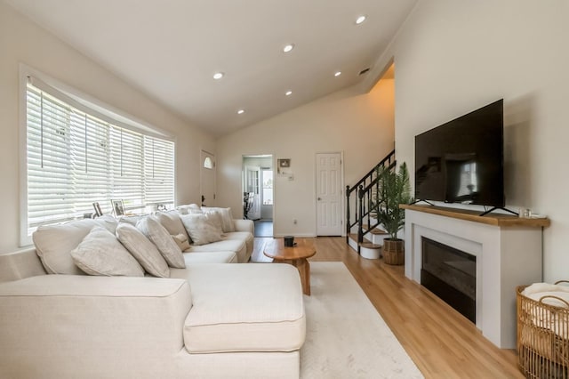 64 W Granada Ave, Lindenhurst, NY 11757 - living area featuring light wood-style floors, stairs, recessed lighting, high vaulted ceiling, and a glass covered fireplace