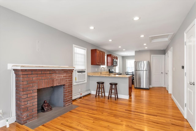 44 Wyoming Ave, Long Beach, NY 11561 - kitchen featuring appliances with stainless steel finishes, a baseboard heating unit, light wood-type flooring, a peninsula, and recessed lighting