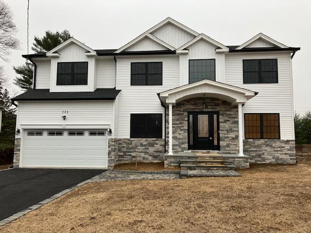 51 Michigan Ave, Massapequa, NY 11758 - view of front facade featuring stone siding, an attached garage, and driveway