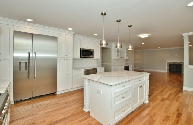 51 Michigan Ave, Massapequa, NY 11758 - kitchen with appliances with stainless steel finishes, a fireplace, white cabinetry, ornamental molding, and light wood-style floors