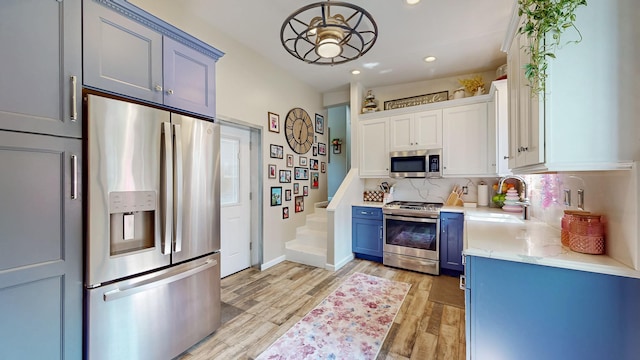 7 Didio Ln, Montgomery, NY 12549 - kitchen featuring appliances with stainless steel finishes, light wood finished floors, blue cabinets, recessed lighting, and tasteful backsplash