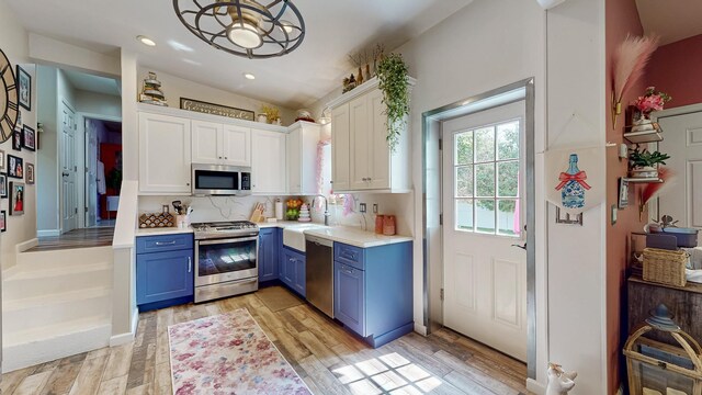 7 Didio Ln, Montgomery, NY 12549 - kitchen featuring stainless steel appliances, blue cabinetry, white cabinets, light countertops, and light wood finished floors