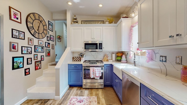 7 Didio Ln, Montgomery, NY 12549 - kitchen featuring stainless steel appliances, blue cabinets, light wood-style flooring, white cabinetry, and tasteful backsplash