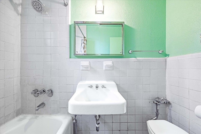 2015 St Paul Ave Unit 3G, Bronx, NY 10461 - bathroom with tile walls, toilet, a sink, shower / bath combination, and a wainscoted wall
