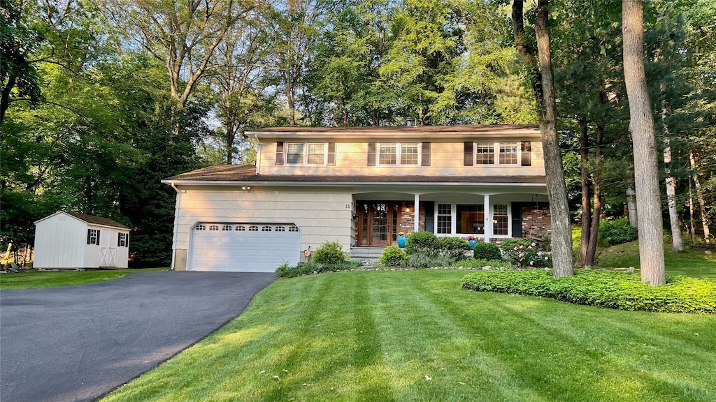 11 Robin Hood Rd, Montebello, NY 10901 - traditional home with driveway, a front lawn, covered porch, and view of wooded area
