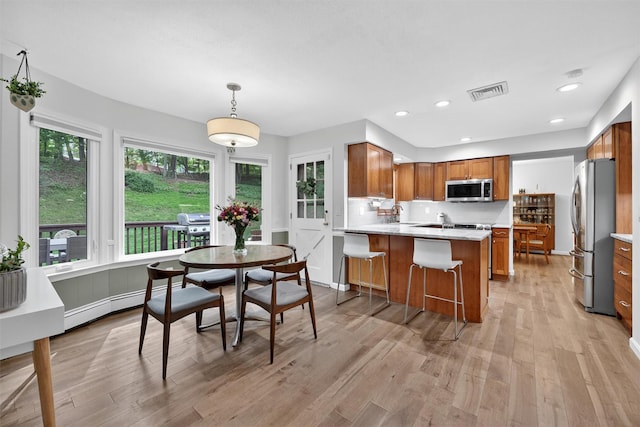 11 Robin Hood Rd, Montebello, NY 10901 - kitchen with appliances with stainless steel finishes, brown cabinets, a baseboard heating unit, a peninsula, and light wood-style floors