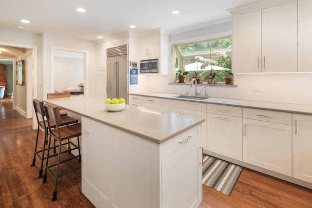 33 High Way, Chappaqua, NY 10514 - kitchen with appliances with stainless steel finishes, a sink, dark wood-style flooring, a kitchen breakfast bar, and tasteful backsplash