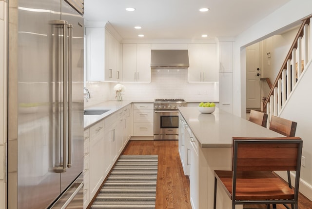 33 High Way, Chappaqua, NY 10514 - kitchen featuring premium appliances, ventilation hood, dark wood-style floors, a kitchen bar, and a sink