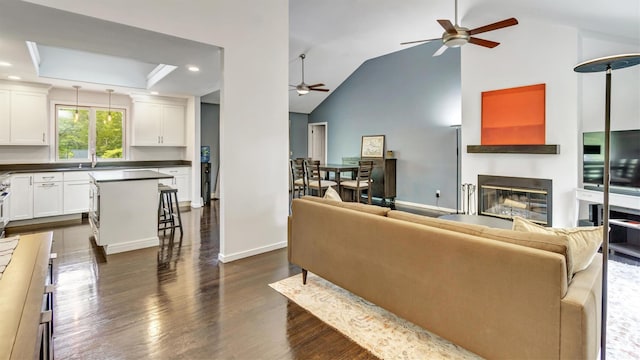 4 Bay View Dr W, Hampton Bays, NY 11946 - living area featuring a ceiling fan, dark wood-style flooring, a glass covered fireplace, high vaulted ceiling, and baseboards