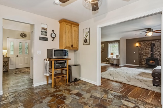 316 Myers Corners Rd, Wappingers Falls, NY 12590 - kitchen featuring a ceiling fan, stainless steel microwave, dark stone finish floors, and a wood stove