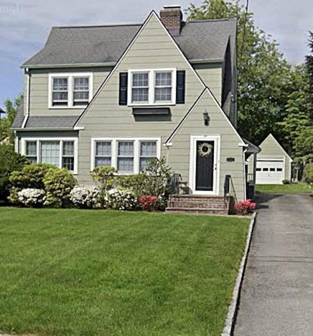 25 Hazelton Dr, White Plains, NY 10605 - view of front facade featuring a detached garage, a chimney, a front lawn, and an outdoor structure