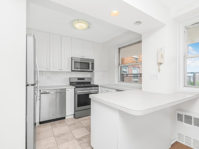 5900 Arlington Ave Unit 6S, Bronx, NY 10471 - kitchen with appliances with stainless steel finishes, radiator, a peninsula, white cabinets, and healthy amount of natural light