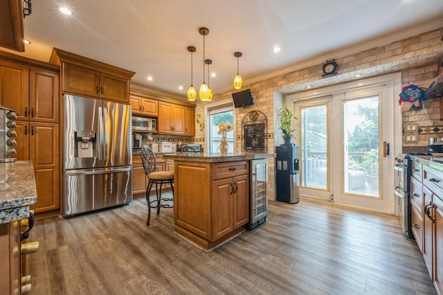 74 Miles Ave, Albertson, NY 11507 - kitchen featuring appliances with stainless steel finishes, beverage cooler, brown cabinets, a kitchen island, and dark wood-style flooring