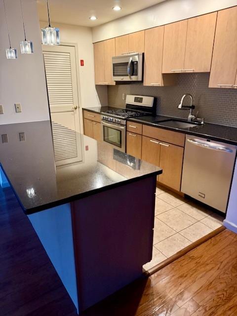 1010 Washington Grn Unit 1010, New Windsor, NY 1255312553 - kitchen featuring appliances with stainless steel finishes, dark countertops, tasteful backsplash, light wood finished floors, and pendant lighting