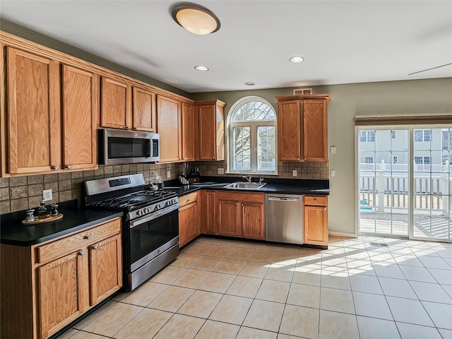 2717 Colonial Dr, New Windsor, NY 12553 - kitchen featuring stainless steel appliances, a sink, dark countertops, decorative backsplash, and brown cabinetry