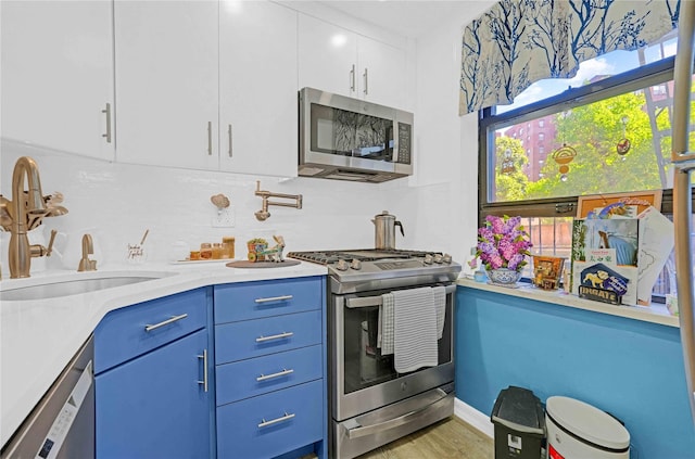 26-25 141th St Unit 1B, Flushing, NY 11354 - kitchen featuring stainless steel appliances, a sink, blue cabinets, decorative backsplash, and white cabinets