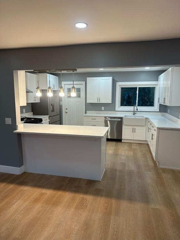 123 Mitchell St, North Bellmore, NY 11710 - kitchen with appliances with stainless steel finishes, a sink, a peninsula, light countertops, and white cabinets