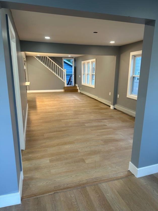 123 Mitchell St, North Bellmore, NY 11710 - unfurnished room with baseboards, baseboard heating, stairway, wood finished floors, and recessed lighting