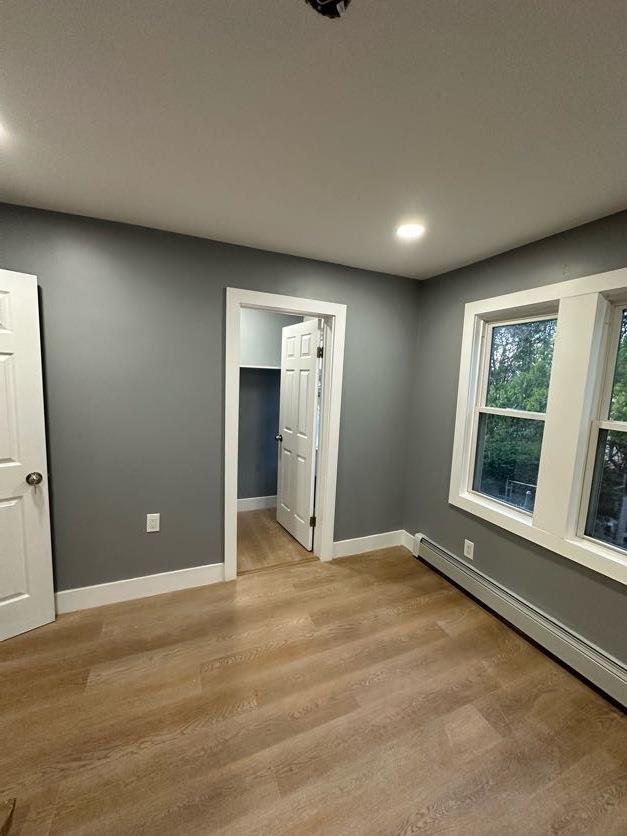 123 Mitchell St, North Bellmore, NY 11710 - empty room with a baseboard radiator, light wood-style floors, baseboards, and recessed lighting