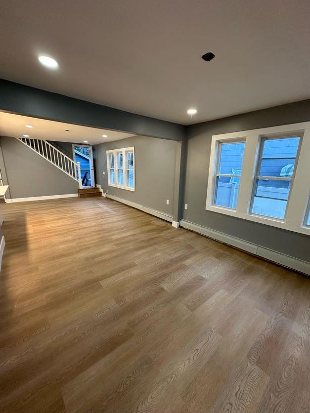 123 Mitchell St, North Bellmore, NY 11710 - unfurnished living room featuring baseboards, stairway, wood finished floors, recessed lighting, and a baseboard heating unit