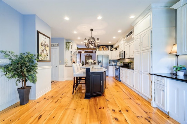 88 Prices Switch Rd, Warwick, NY 10990 - kitchen featuring appliances with stainless steel finishes, a chandelier, white cabinets, light wood finished floors, and a kitchen bar