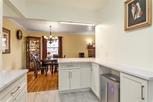 590 Langley Ave, West Hempstead, NY 11552 - kitchen featuring a chandelier, a peninsula, white cabinetry, crown molding, and hanging light fixtures